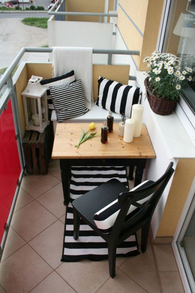 Bộ bàn ghế rất giản dị nhưng sự lựa chọn gối dựa, thảm để chân  ​và cách bày đặt bình hoa, nến giúp không gian nhỏ đáng yêu hơn